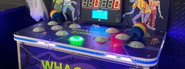 Whack a Zombie arcade unit with purple zombie graphics, glowing dome targets and a hammer