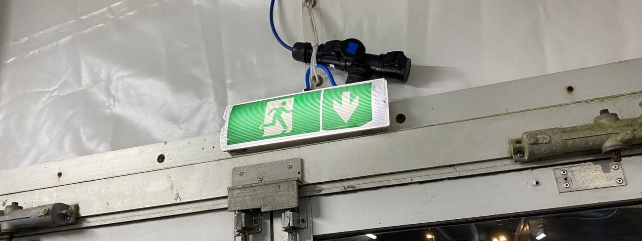 Green LED emergency exit sign mounted above a sliding door inside a marquee