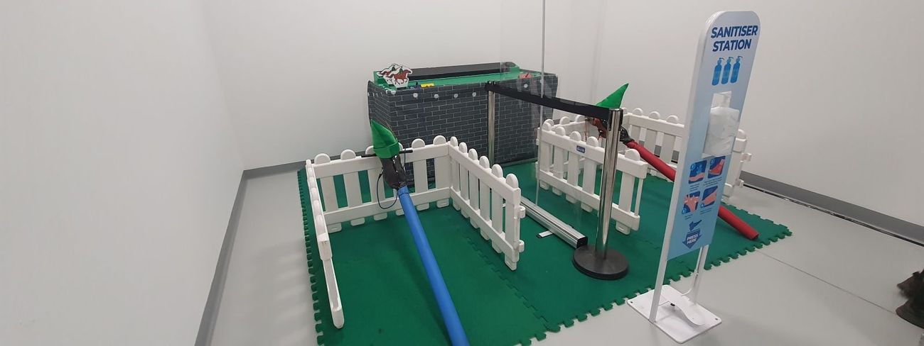 Gold Cup horse racing arena set up in a warehouse with picket fencing, a starting post and sanitiser station