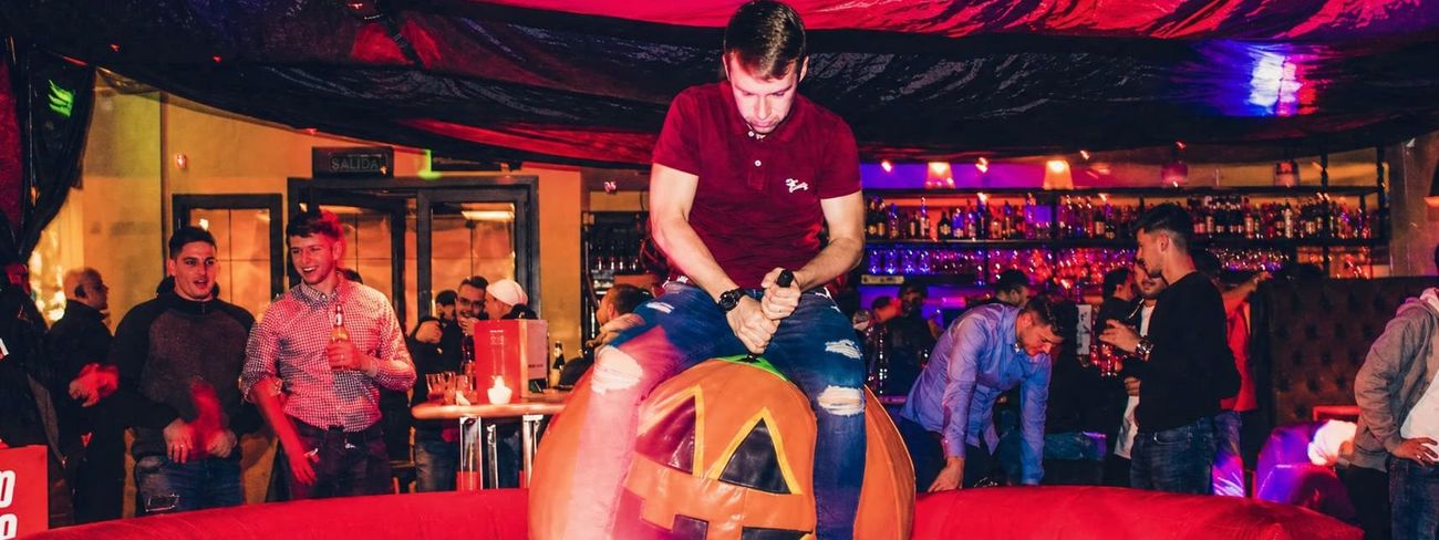 Halloween rodeo pumpkin inflatable in use at a bar event under red ceiling drape