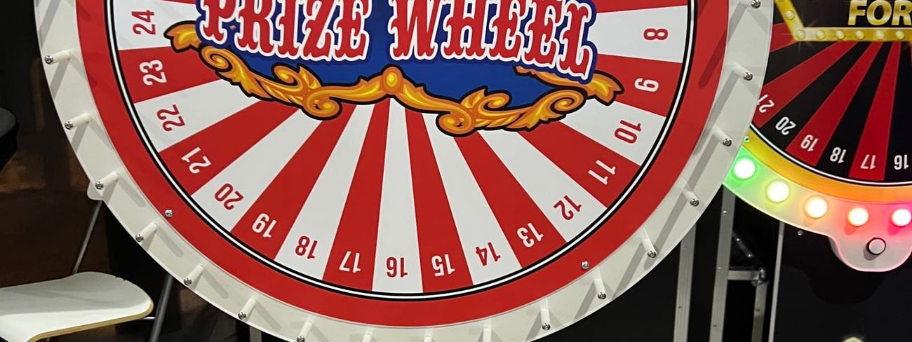 Red and white circus-style Prize Wheel beside an LED Wheel of Fortune at an event