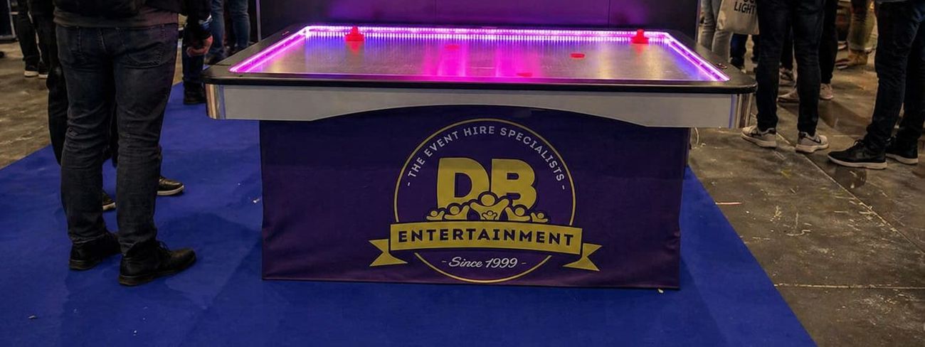 Air hockey table with pink LED edge lighting and DB Entertainment branded skirt at an exhibition