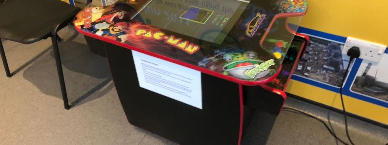 Retro cocktail arcade table set up indoors for guests to sit and play