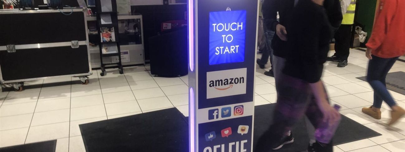 Selfie pod at an Amazon fulfilment centre entrance with staff walking past