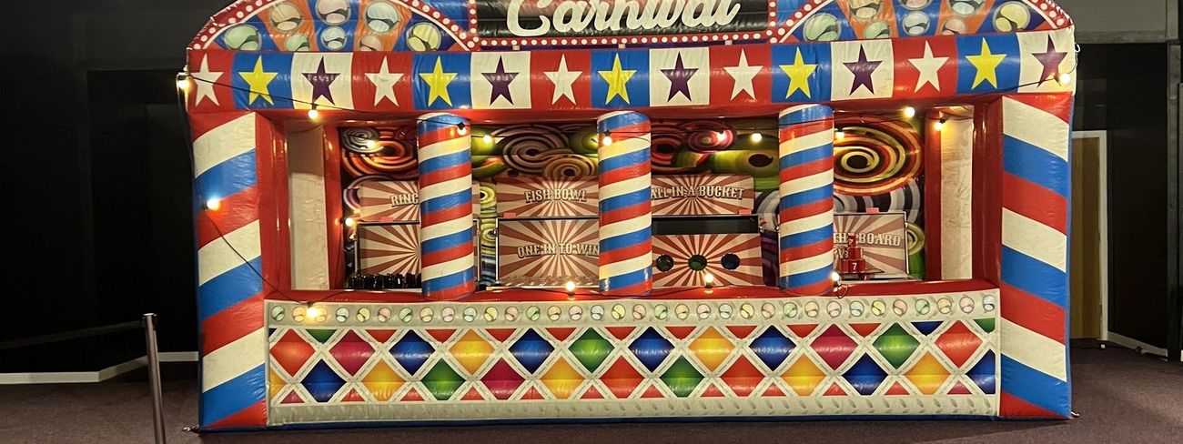 Grand carnival fun fair stalls under spotlit stage lighting at an evening corporate event