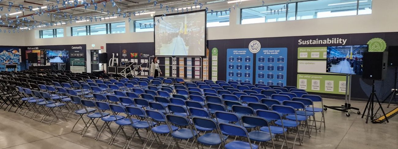 Rows of black event chairs facing a large screen at an Amazon corporate event