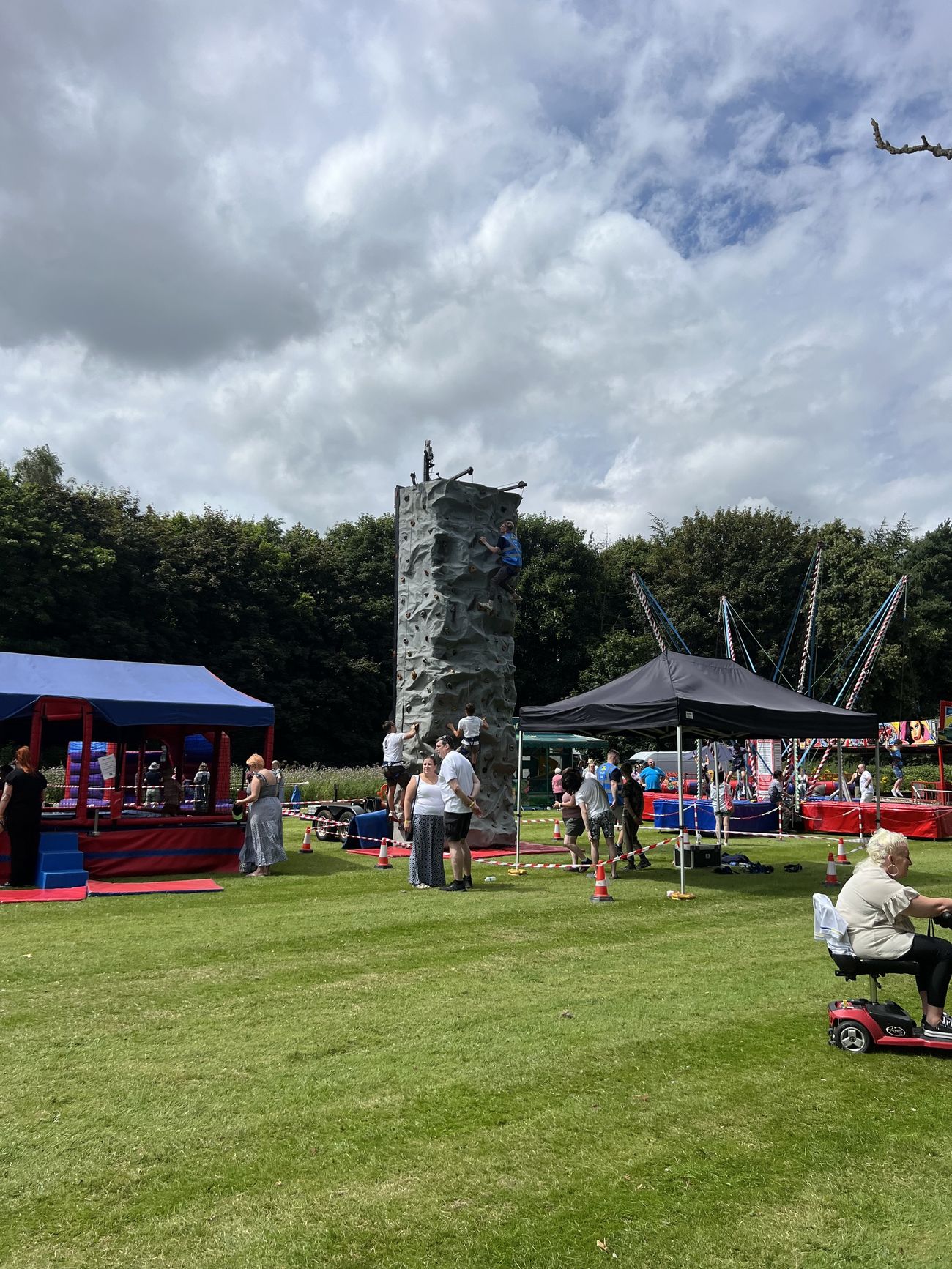 Outdoor community event with a mobile climbing wall and surrounding attractions