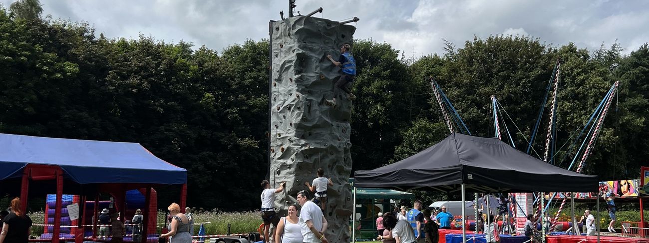 Outdoor community event with a mobile climbing wall and surrounding attractions