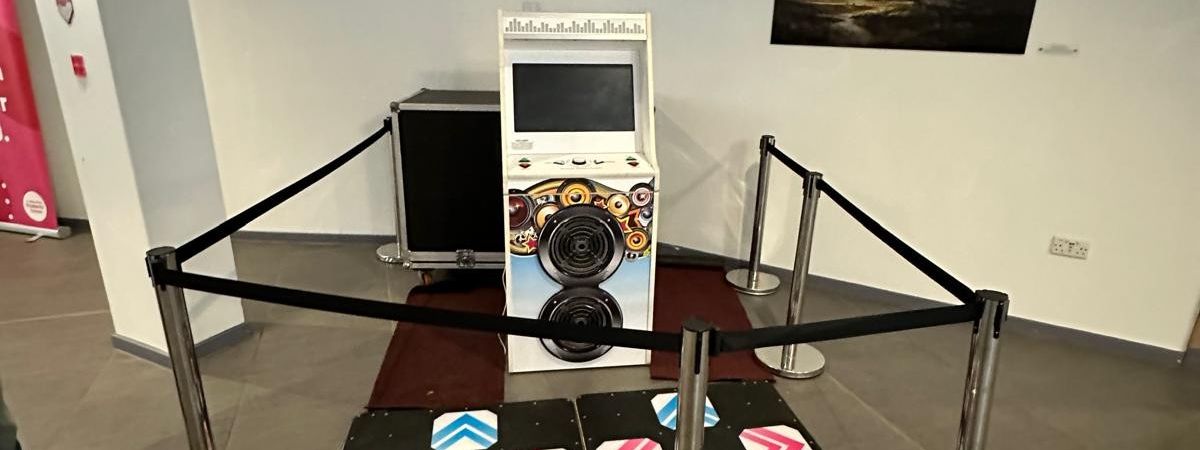 Twin-pad dance arcade machine with 42-inch LED screens and arcade lighting at an exhibition