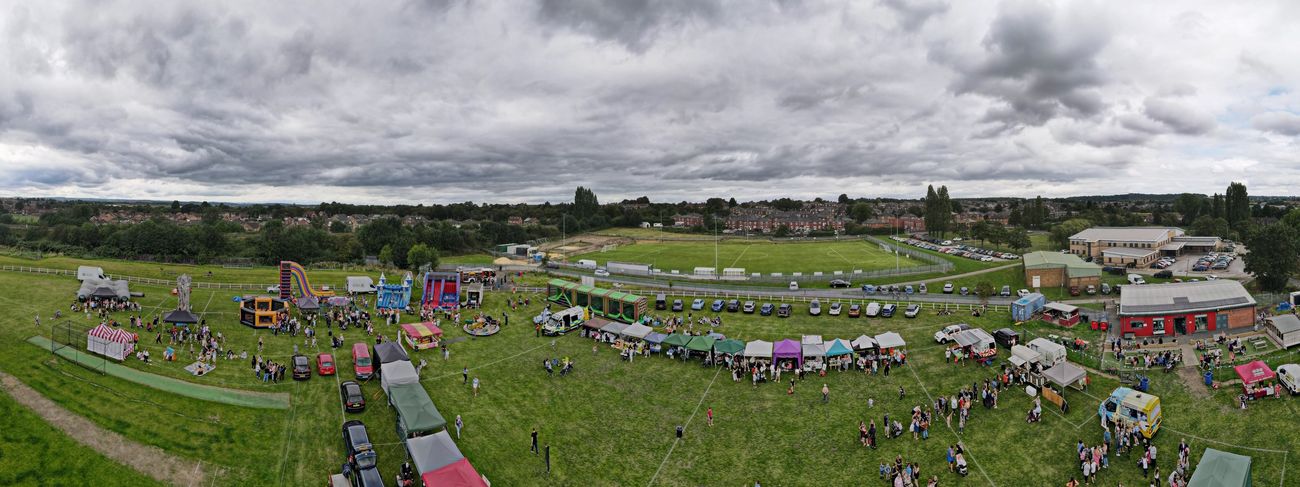 Wide panorama of a large outdoor event with multiple attractions