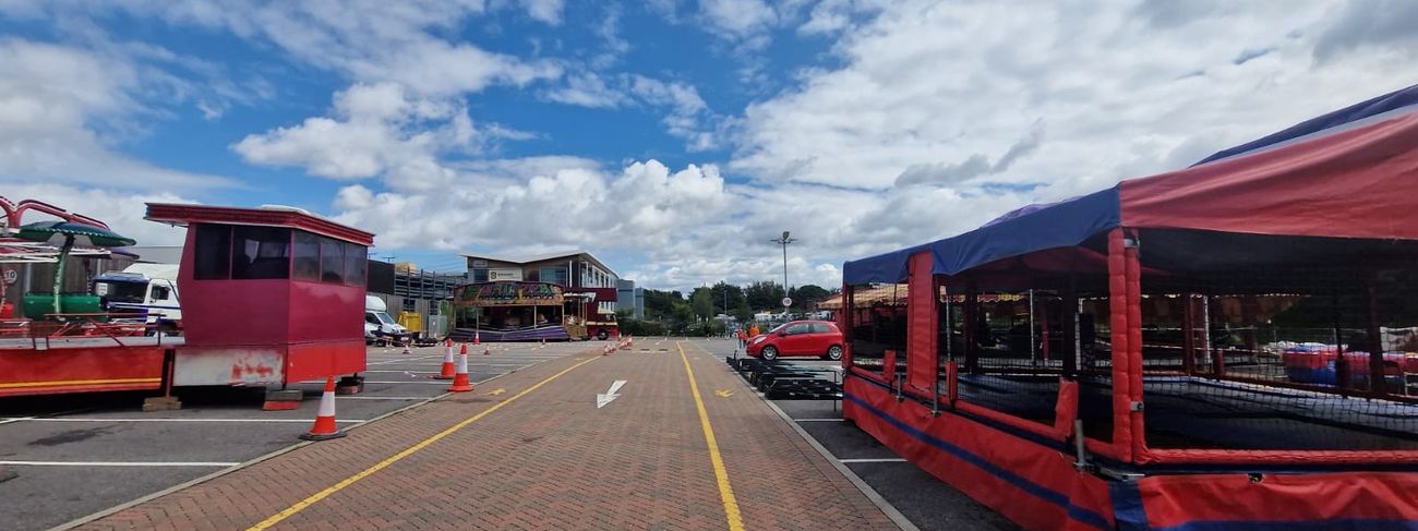 Wide overview of an Amazon-branded funfair event with multiple games, rides and stalls