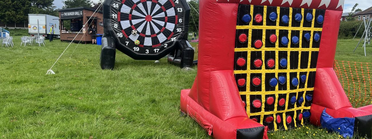 Inflatable Connect 4 unit on grass at an outdoor event alongside a giant inflatable dartboard