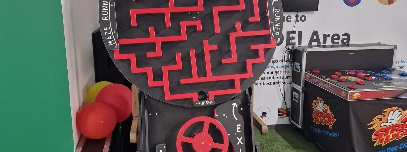 Maze Runner rotating labyrinth game at a Black History Me DEI event, alongside a Strike a Light game