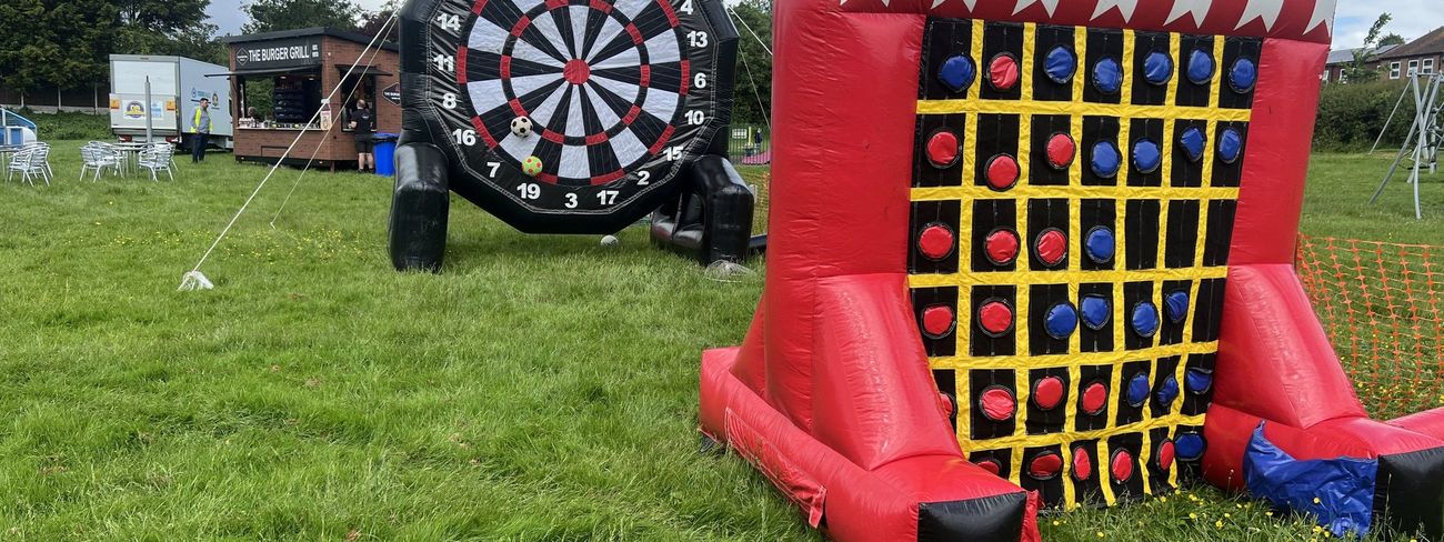 Inflatable Connect 4 game on grass beside a giant inflatable dartboard