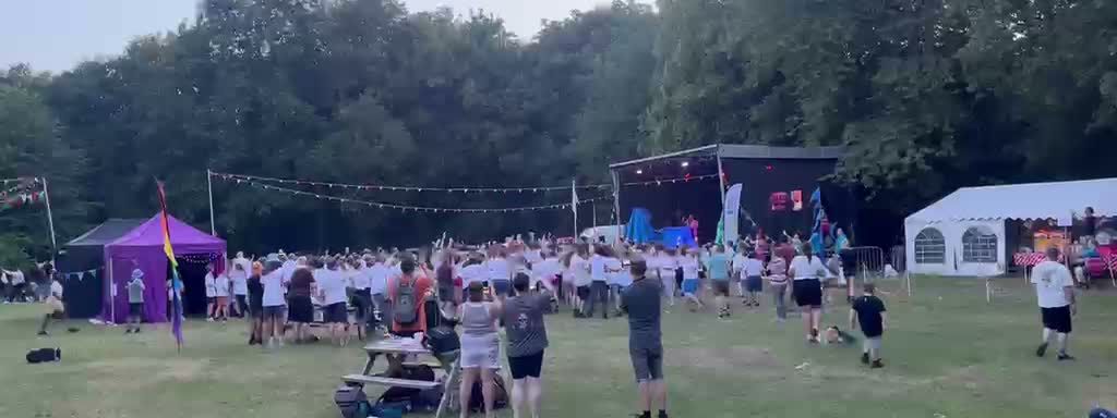 Wide field view of an outdoor stage and PA at HesFest 2026 with a large audience in front