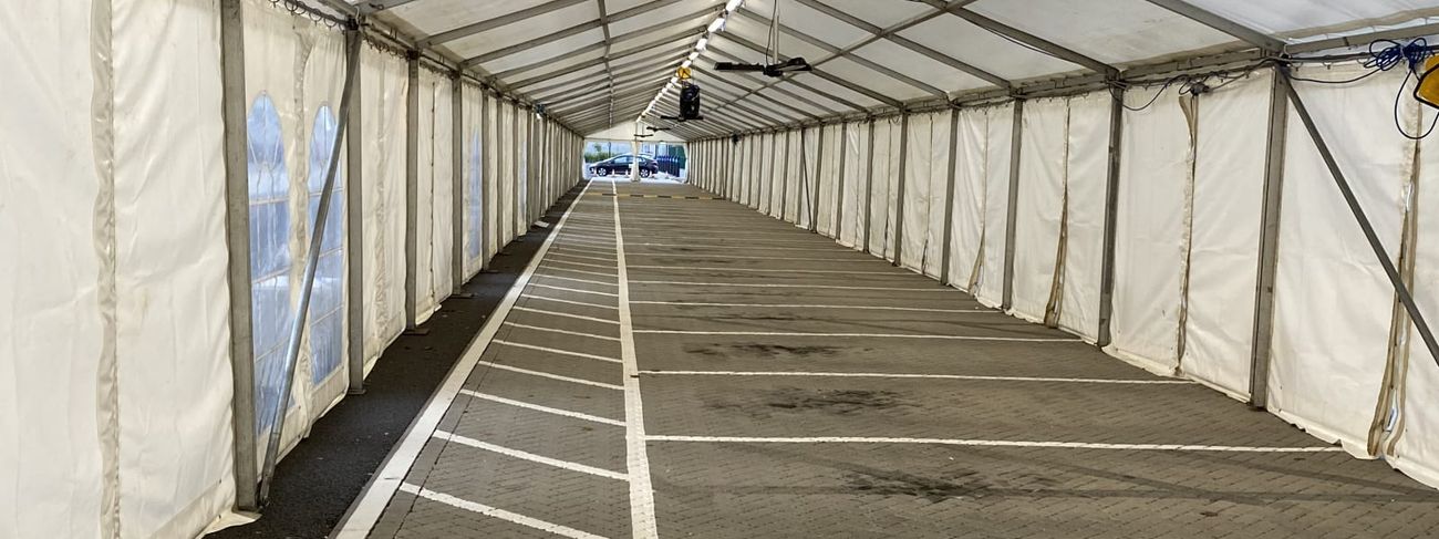 Long marquee walkway lit by rows of overhead 5ft LED strip lights