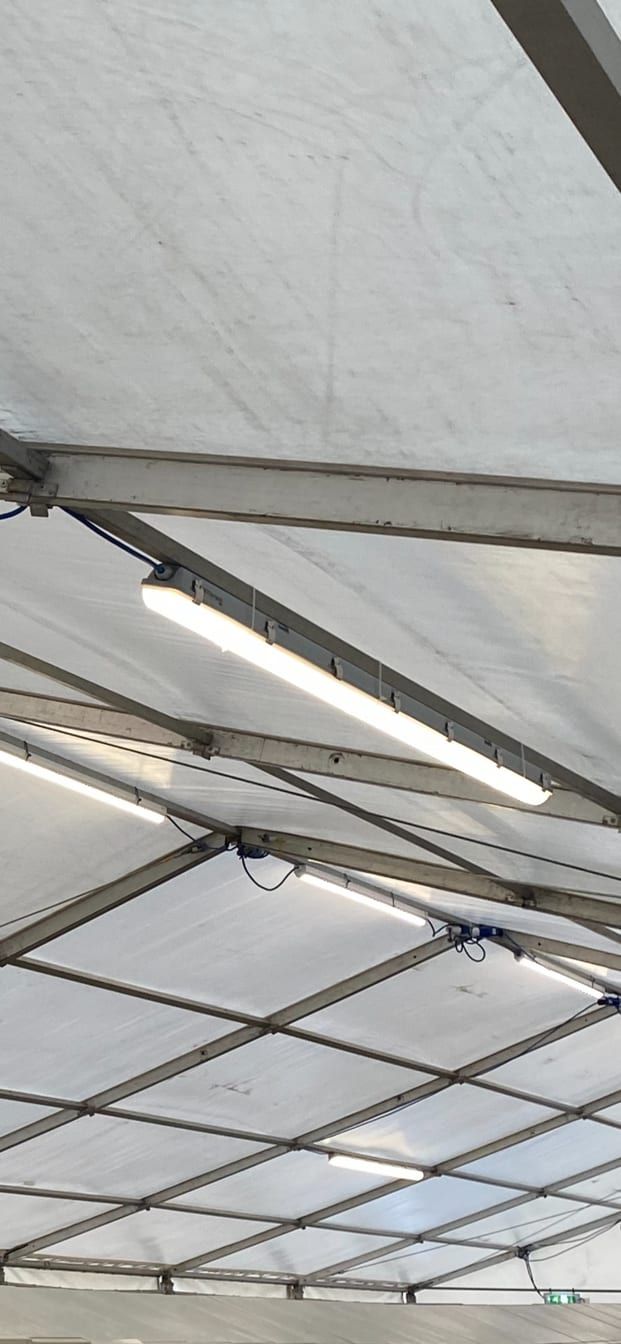 6ft LED batten light installed on a marquee crossbeam looking up at the white roof panels