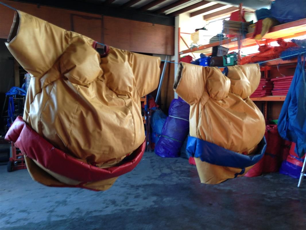 Two adult padded sumo suits, one with a red belt and one with a blue belt