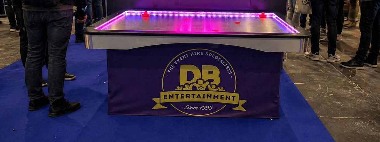 Air hockey table with pink LED edge lighting and DB Entertainment branded skirt at an exhibition
