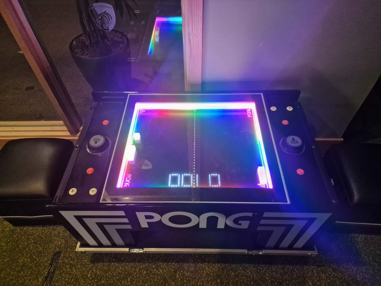 Top-down view of the Atari Pong table mid-game with rainbow LED edges