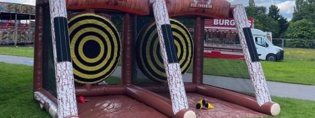 Inflatable axe throwing lanes with target boards and soft velcro axes at an outdoor event