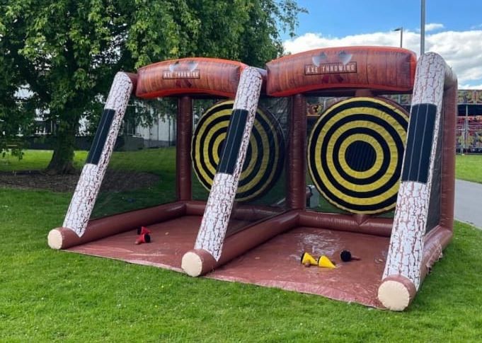 Two players throwing soft axes at velcro target boards inside an inflatable surround