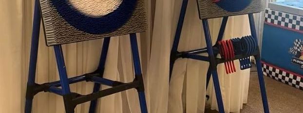 Two soft-axe throwing target boards on blue stands in front of white drape curtains
