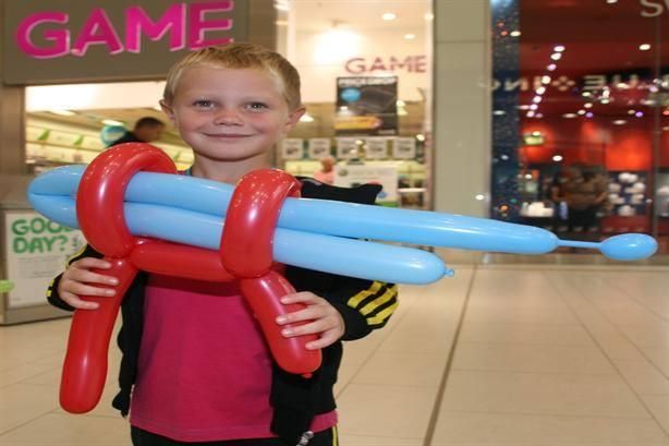 Red and blue balloon ray gun sculpture held by a visitor at a shopping centre event