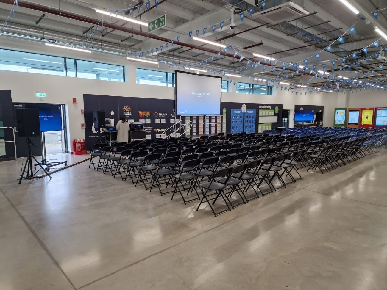 Black foldable chairs in rows facing a projector at an event venue
