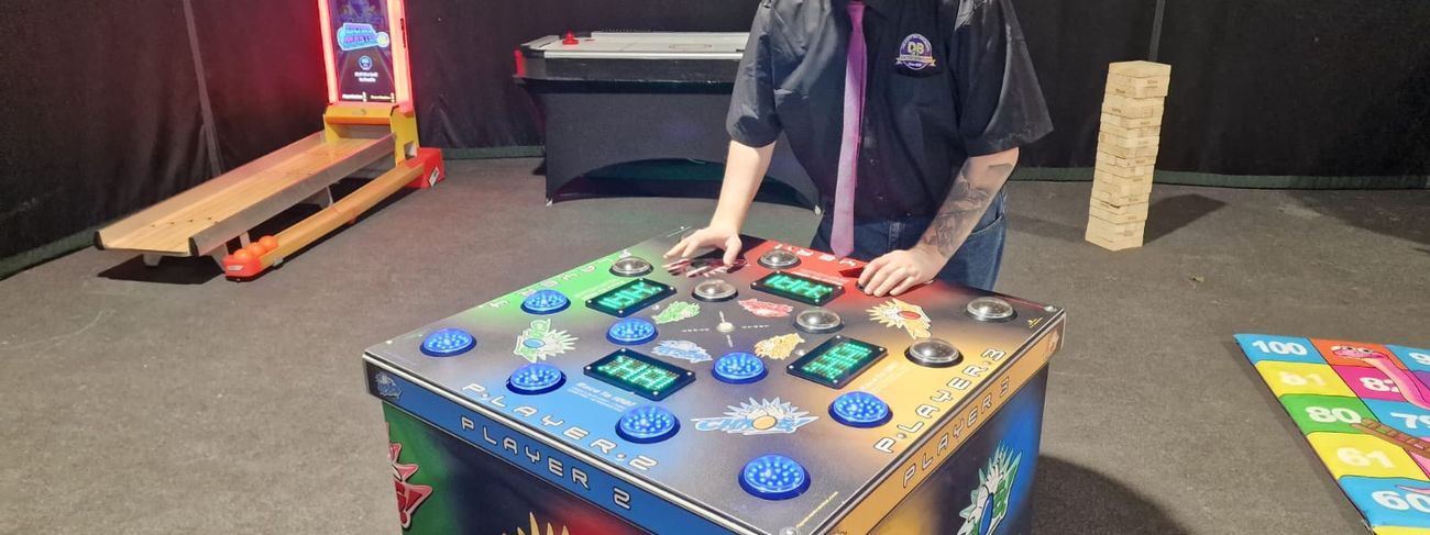 DB Entertainment operator demonstrating the Chaos 4 Player Strike a Light game in the showroom, blue LED buttons lit on the Player 2 section