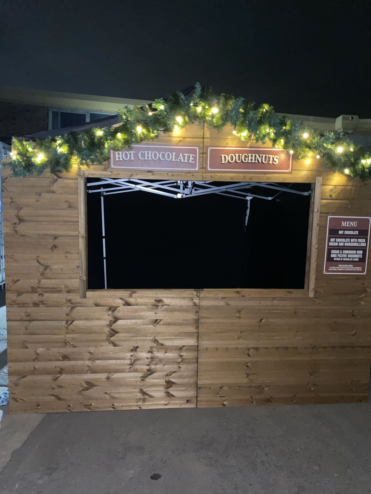 Christmas market stall trading after dark with illuminated garland and serving hatch