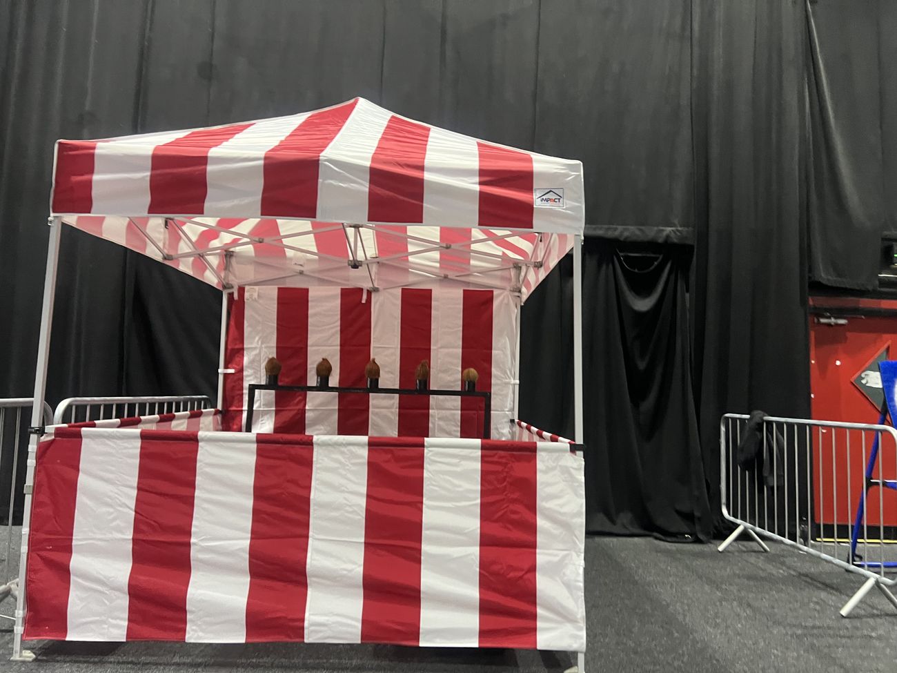 Complete red and white coconut shy stall with five coconuts ready indoors