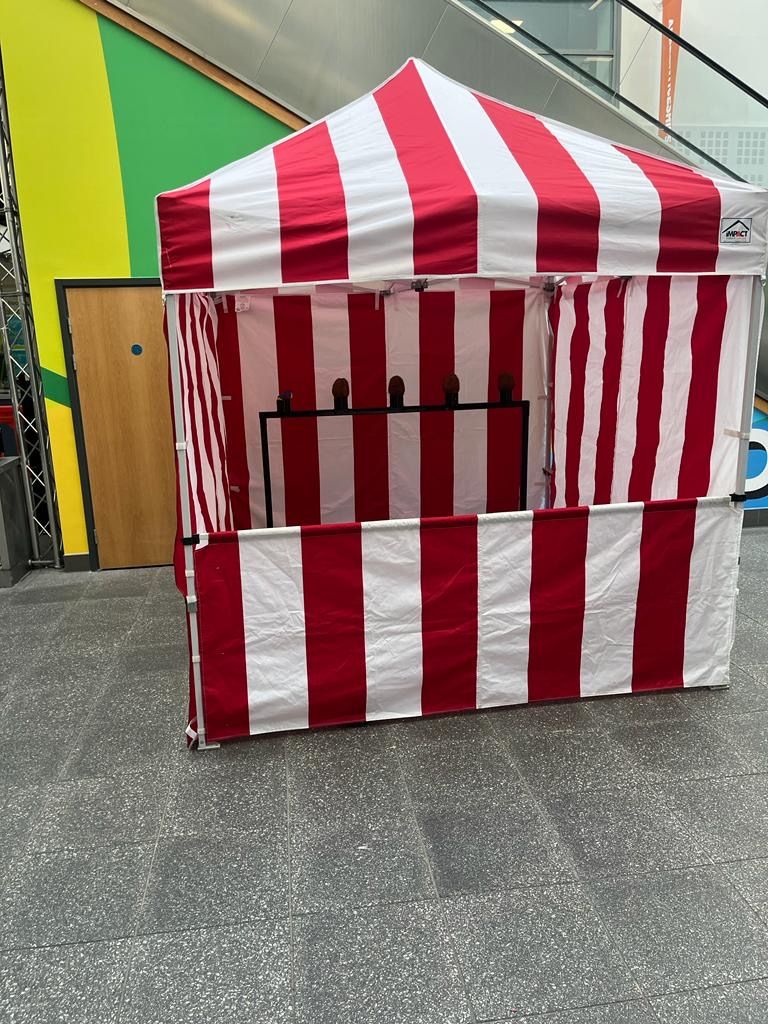 Red and white coconut shy stall with five coconuts ready for play