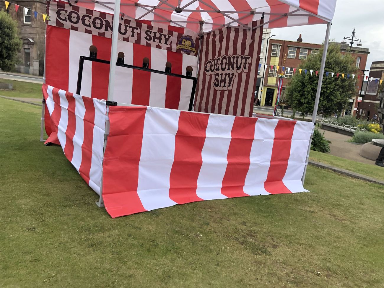 Coconut shy stall with striped front barrier and five coconut targets