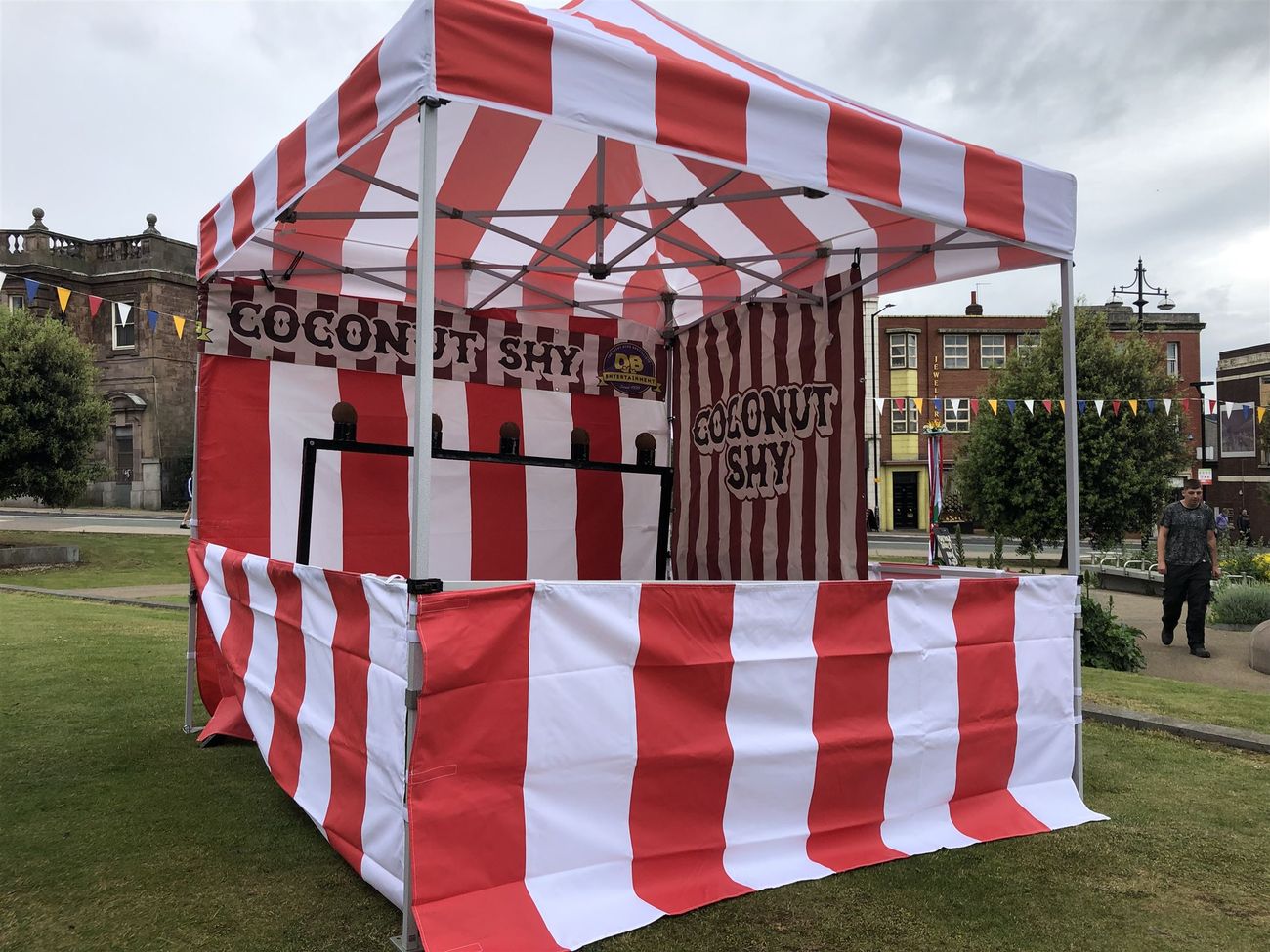 Side view of the red and white striped coconut shy stall and target stand