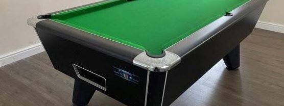Black commercial pool table with green baize on a hard wood floor