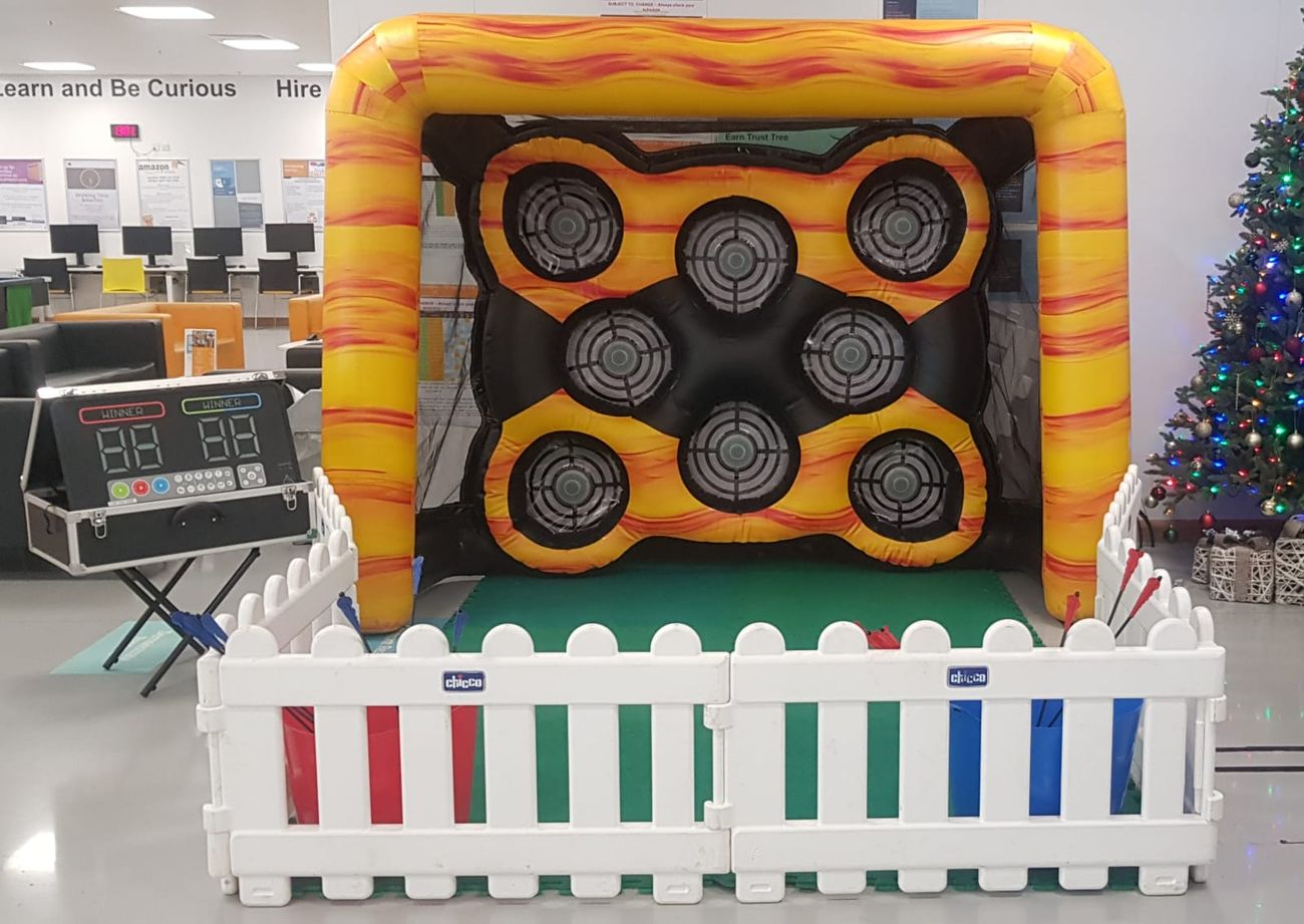 Yellow inflatable archery arena with eight target sensors, control suitcase and white picket fence in front
