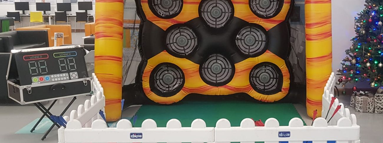 Yellow inflatable archery arena with eight target sensors, control suitcase and white picket fence in front