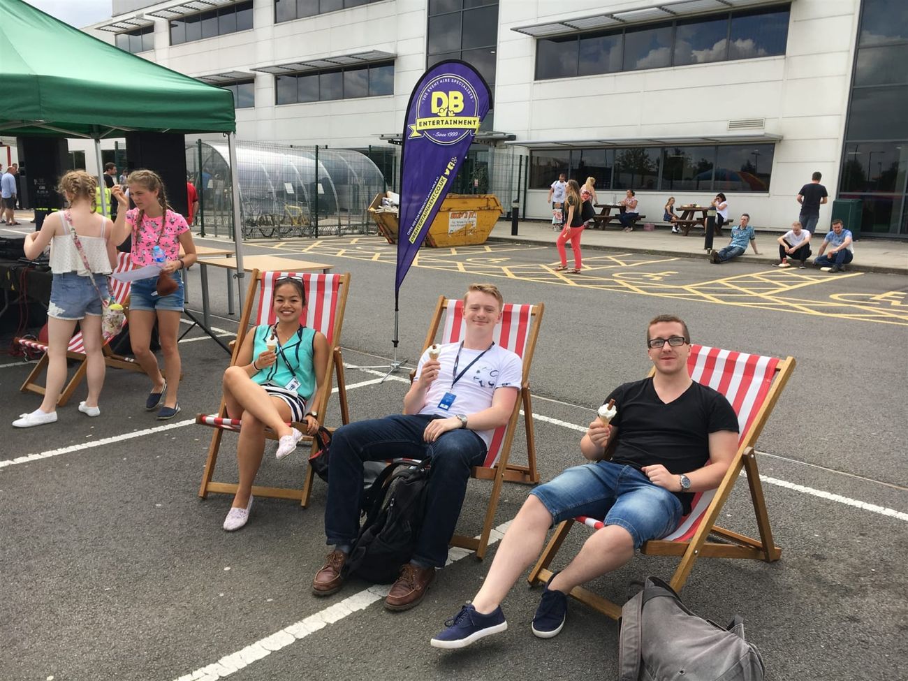 Three colleagues eating ice creams in red striped deck chairs