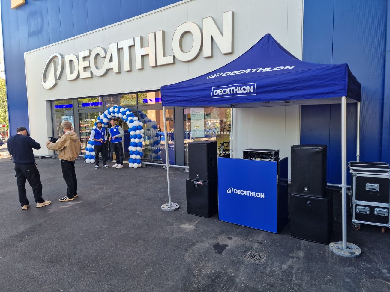 Branded DJ booth set up under a gazebo with a balloon arch at a store launch