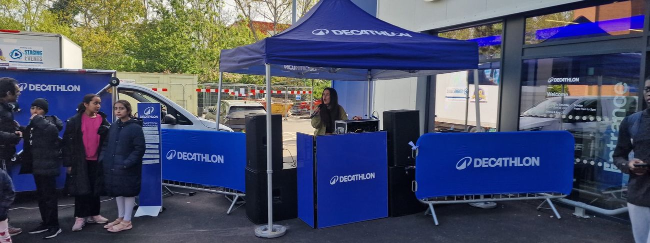Branded DJ booth with custom panel artwork and PA speakers either side at a store launch