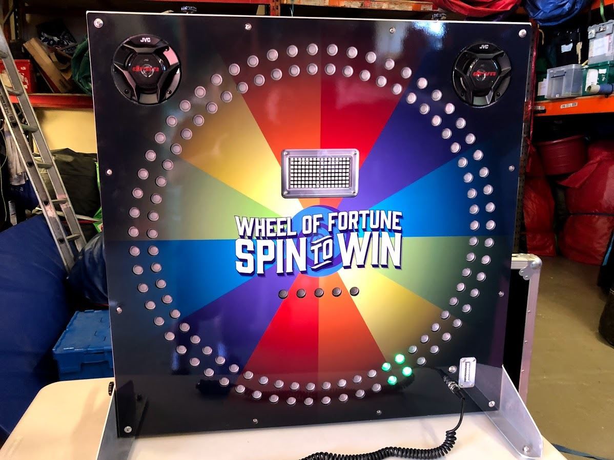 Front-on view of the Electronic Wheel of Fortune cabinet with rainbow segments lit and twin speakers at the top