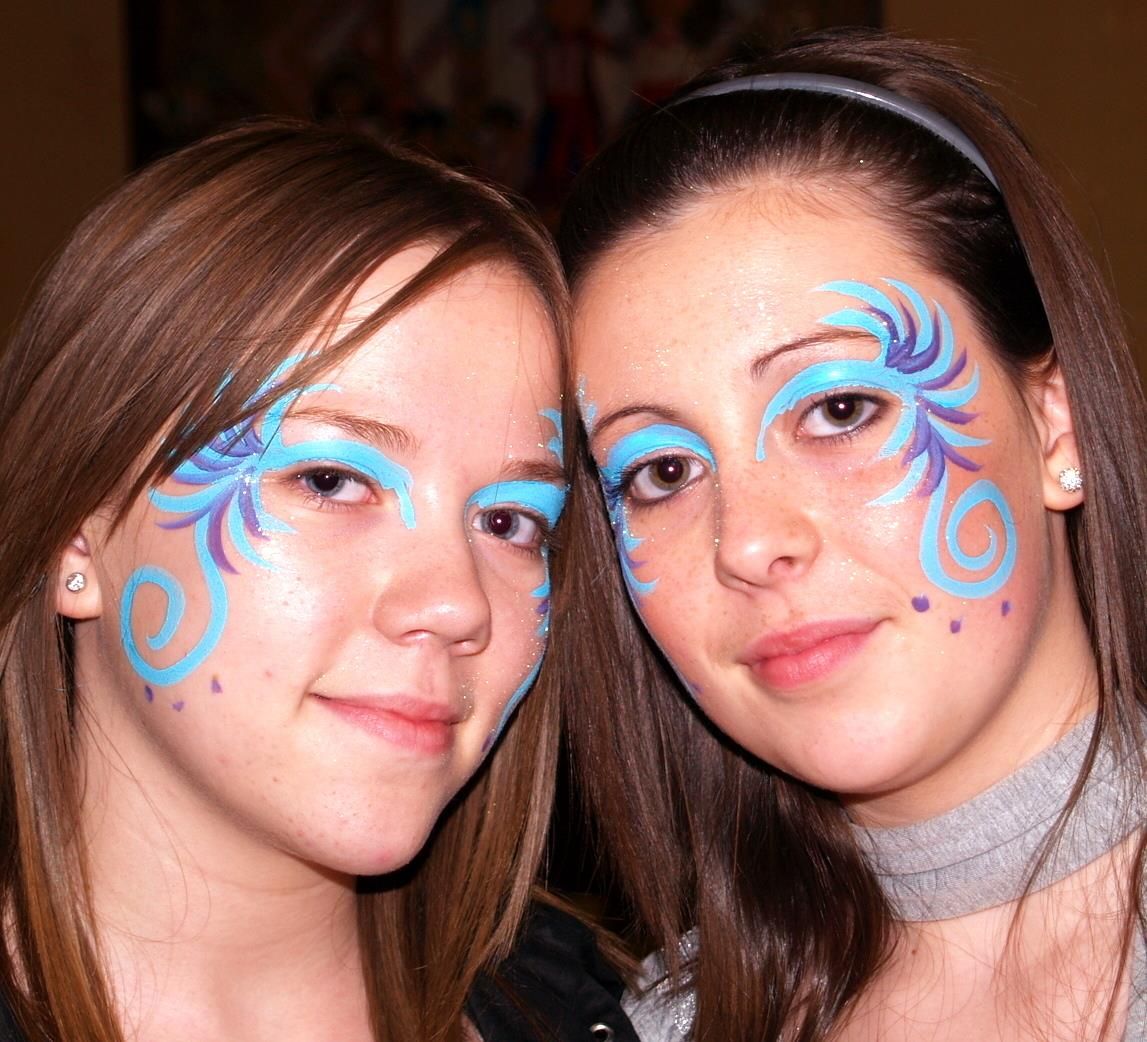 Two adult women with matching blue and silver theatrical mask face paint