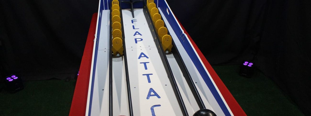 Blue and white Flap Attack two-lane carnival game with yellow scored flaps and red and black bowling balls in the starting cradles