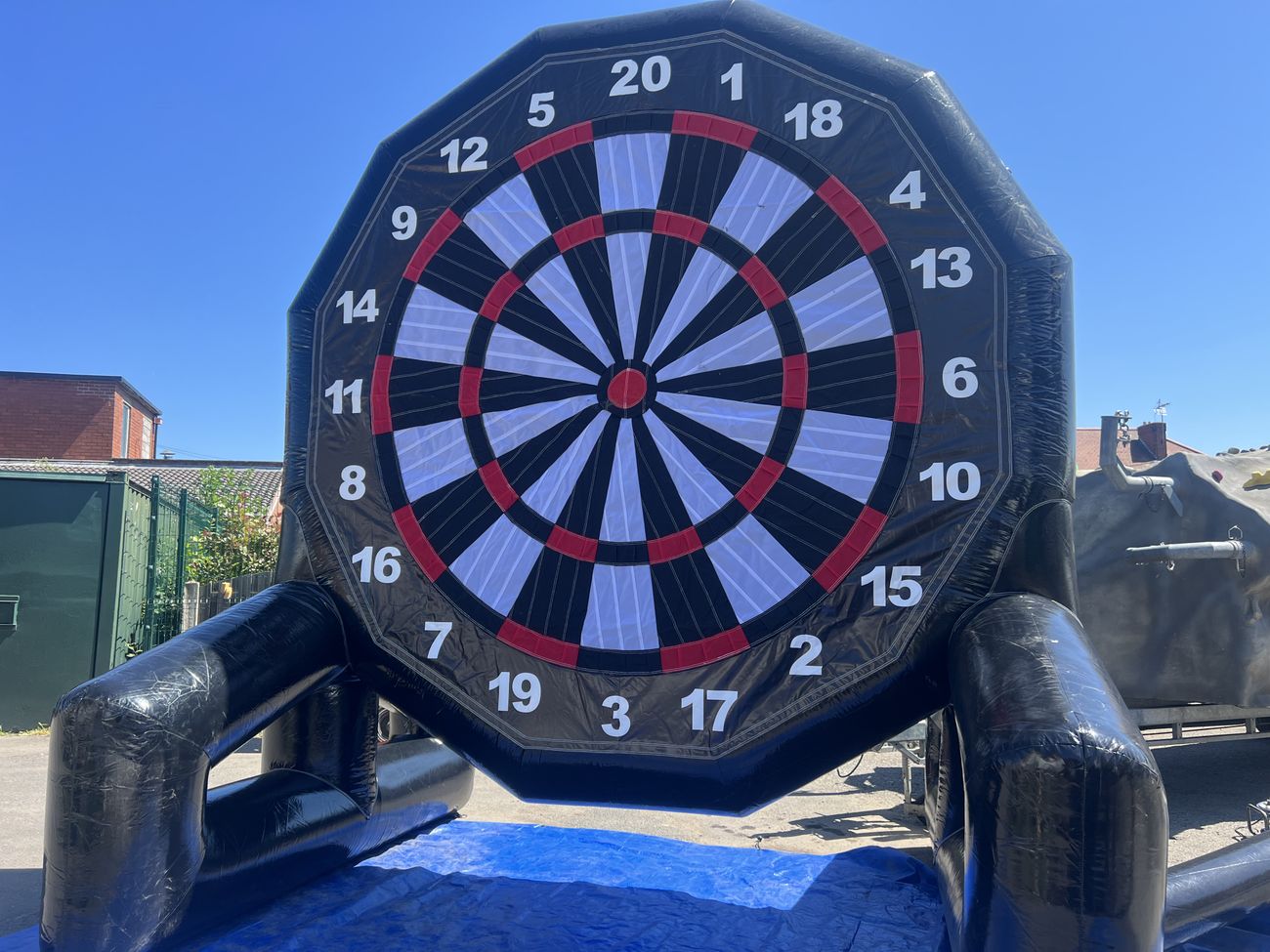 Player kicking a velcro football at a giant inflatable dartboard at an outdoor event