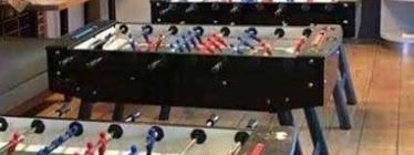 Three commercial football tables set up side by side at a barn venue event