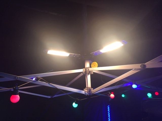 Heater arms glowing beneath a festoon-lit gazebo frame at night