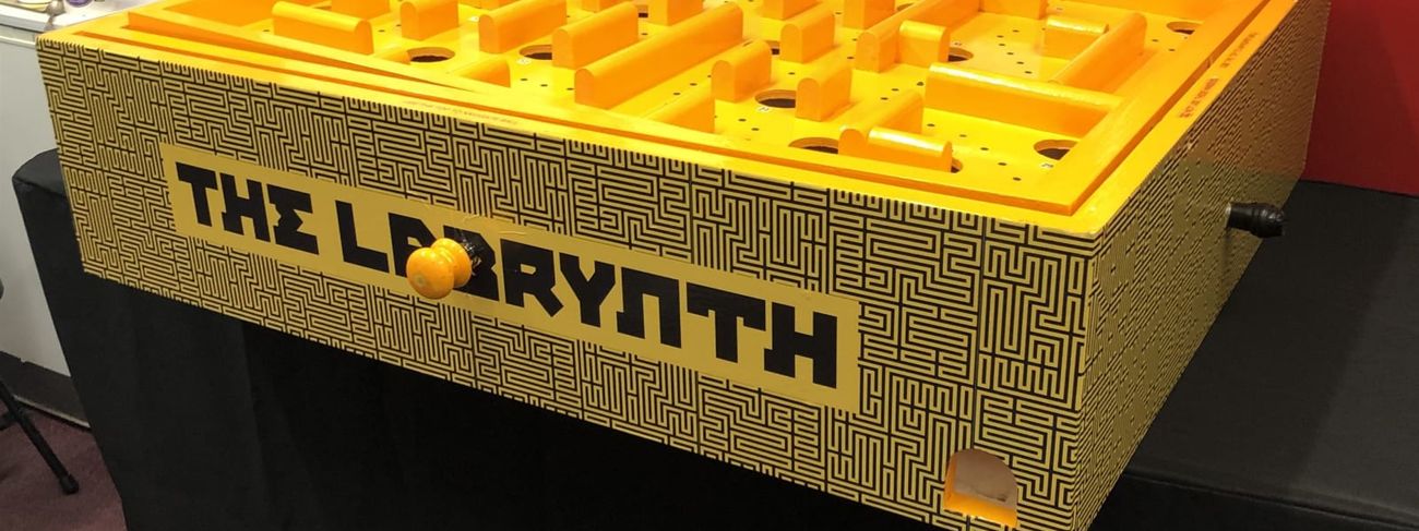 Giant Labyrinth tilting maze game - yellow and black maze-patterned unit with raised wall playing surface, photographed in the showroom