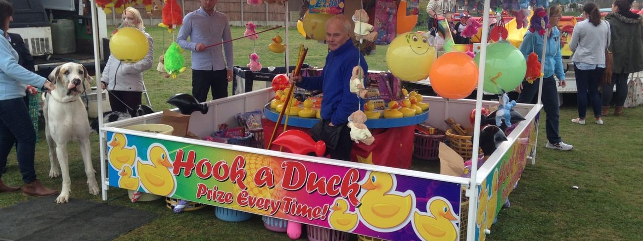 Hook A Duck stall with a "prize every time" banner at an outdoor community event