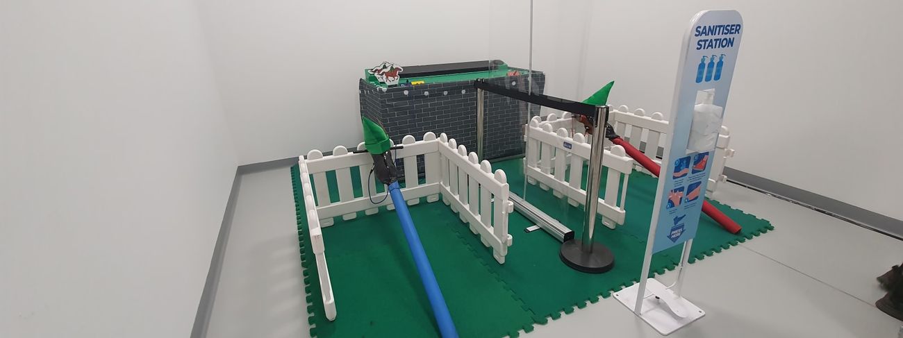 Gold Cup horse racing arena set up in a warehouse with picket fencing, a starting post and sanitiser station